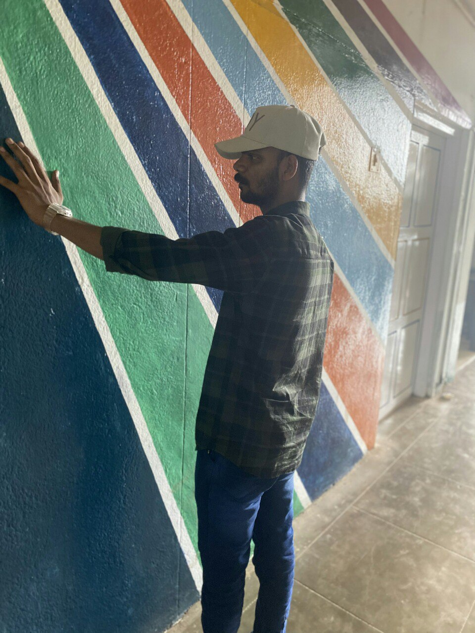 a man standing in front of a wall with a rainbow design